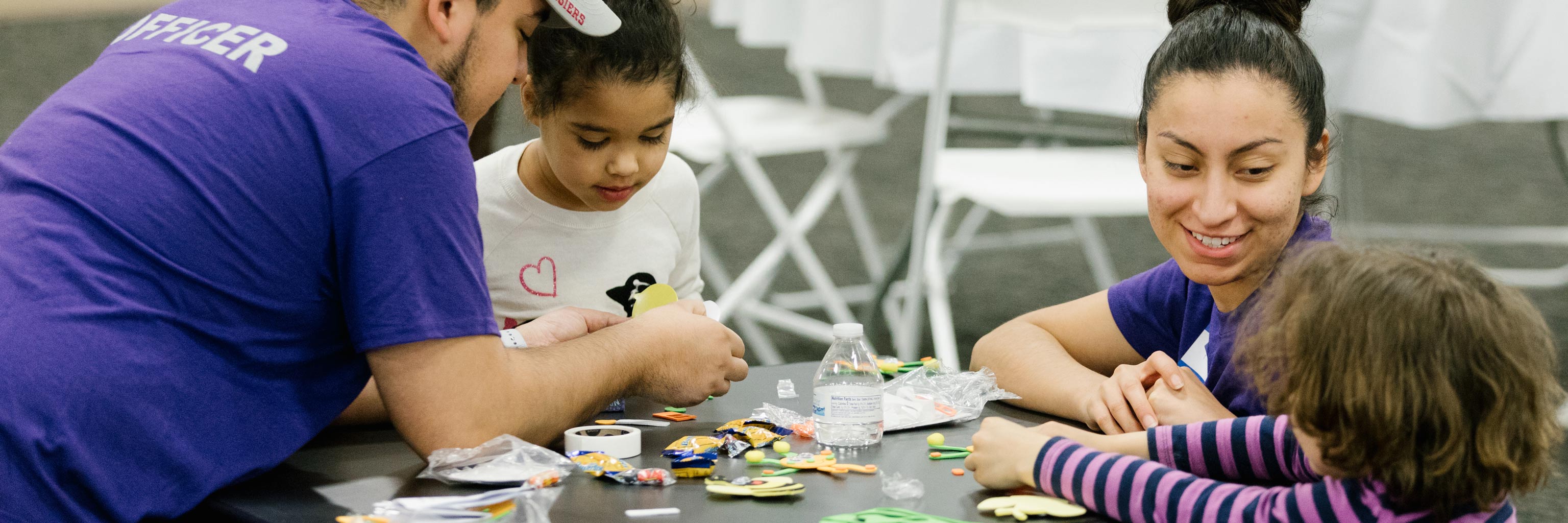 Two WOKE club members doing a craft project with two young children