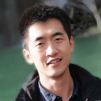 A headshot of Yingjian Liang, who wears a black jacket and poses outside.