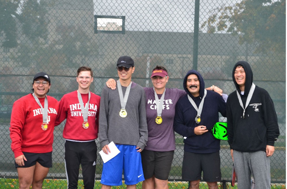 Graduate students pose together on a tennis court on IU's campus.