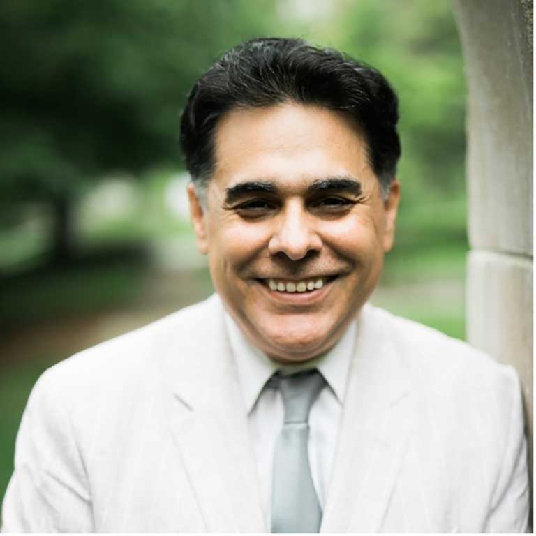 A headshot of Professor Fabio Rojas, who wears a white linen suit and a grey tie.