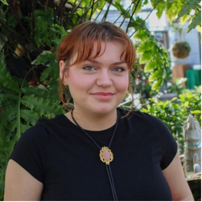 A headshot of Amber Nacyk, who wears a black shirt and poses outside.