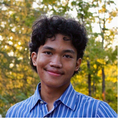 A headshot of Kemal Perdana, who wears a blue stripped dress shirt.