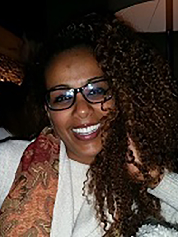 A headshot of Muna Adem, who wears a white sweater and a scarf.