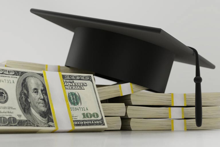 Graduation cap on top of stacks of cash